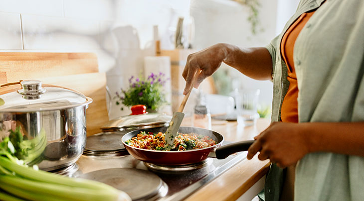 woman cooking vegetables in a pan on the stove