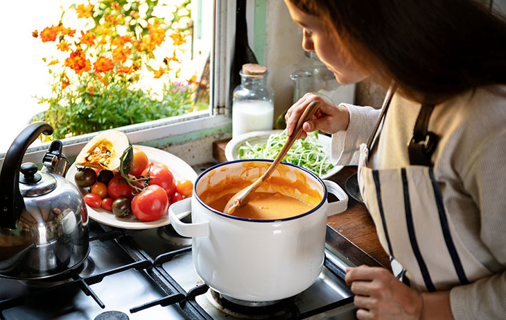 woman making soup on a stove
