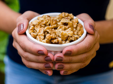 two hands holding a bowl of walnuts