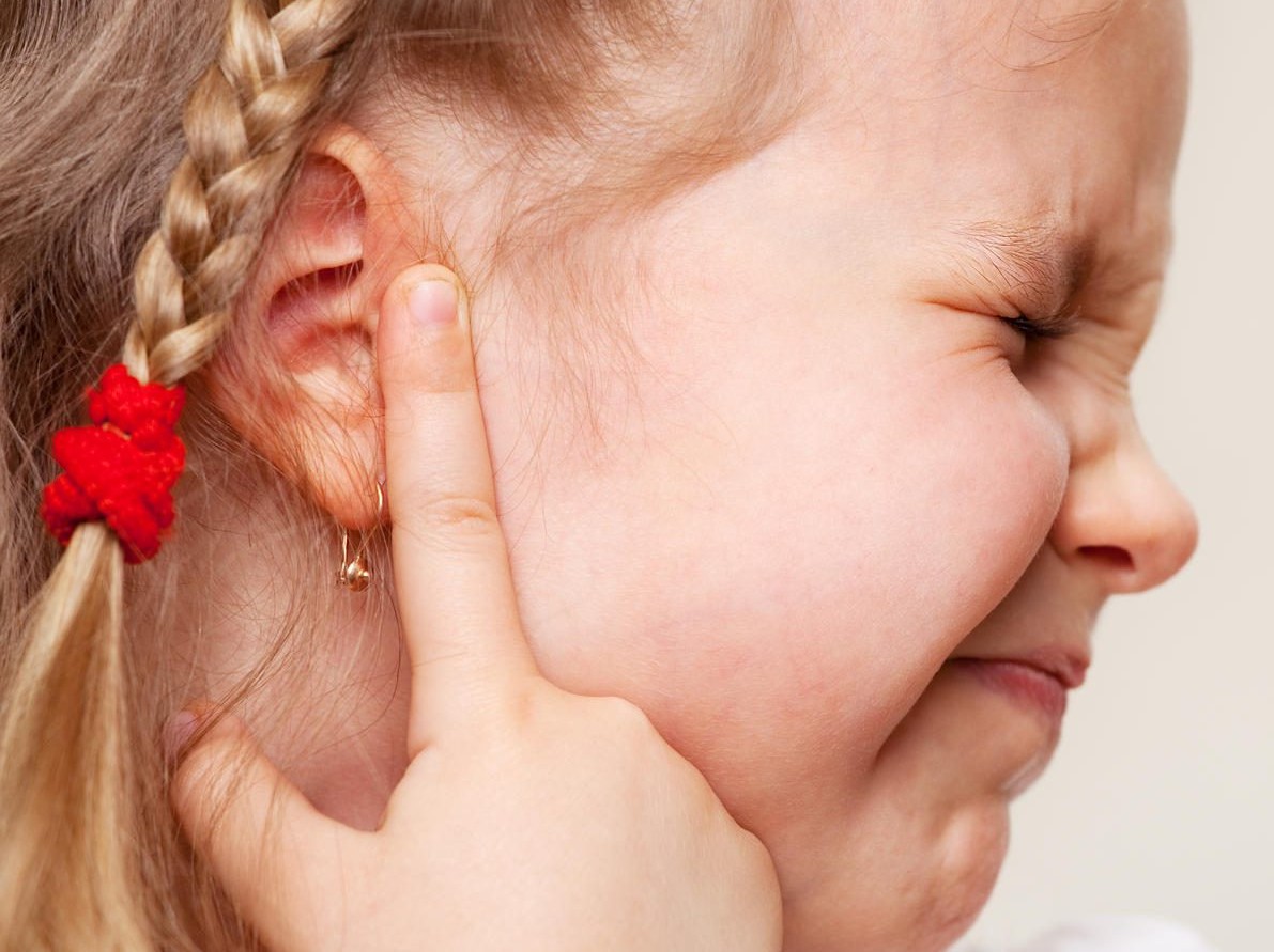 girl holding ear