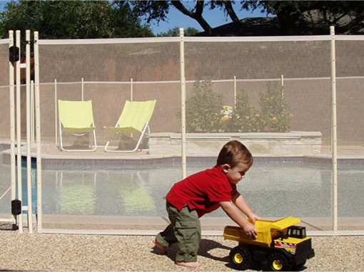 kid pushing toy outside pool gate