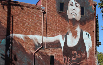 Mural on a brick wall depicts a woman in a black tank top that reads "Oak Park."