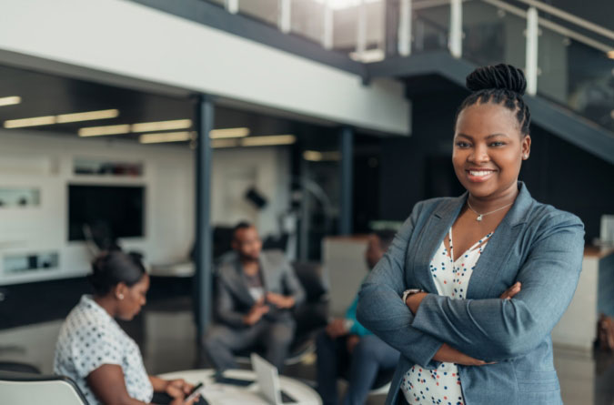 woman standing with arms crossed smiling at camera in an office setting
