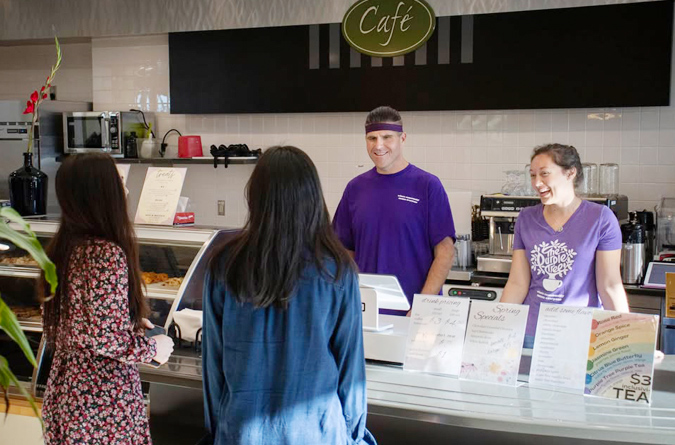 Purple tree cafe counter with staff and customers.