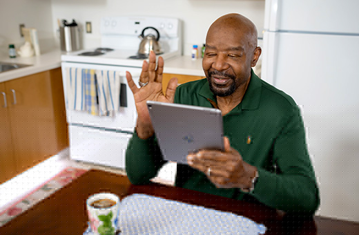 Man at home sitting at kitchen table with laptop and getting telehealth express care