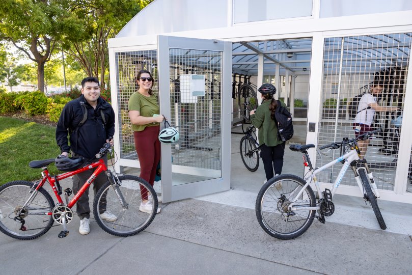 college students bringing bikes into a bike shelter