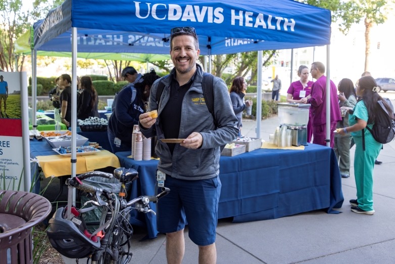 employee posing next to bike with breakfast in hand