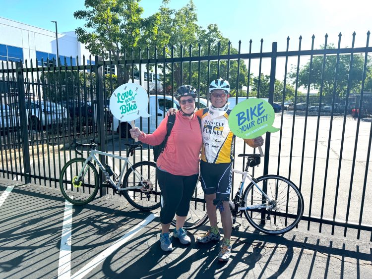employees posing with their bicycles, holding signs that say "love your bike" and "bike your city"