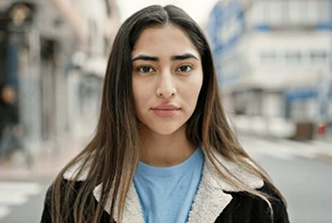 stock image of a young woman, pensive, standing in a city street