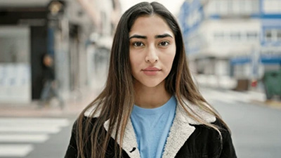 stock image of young woman with pensive look, standing on a city street